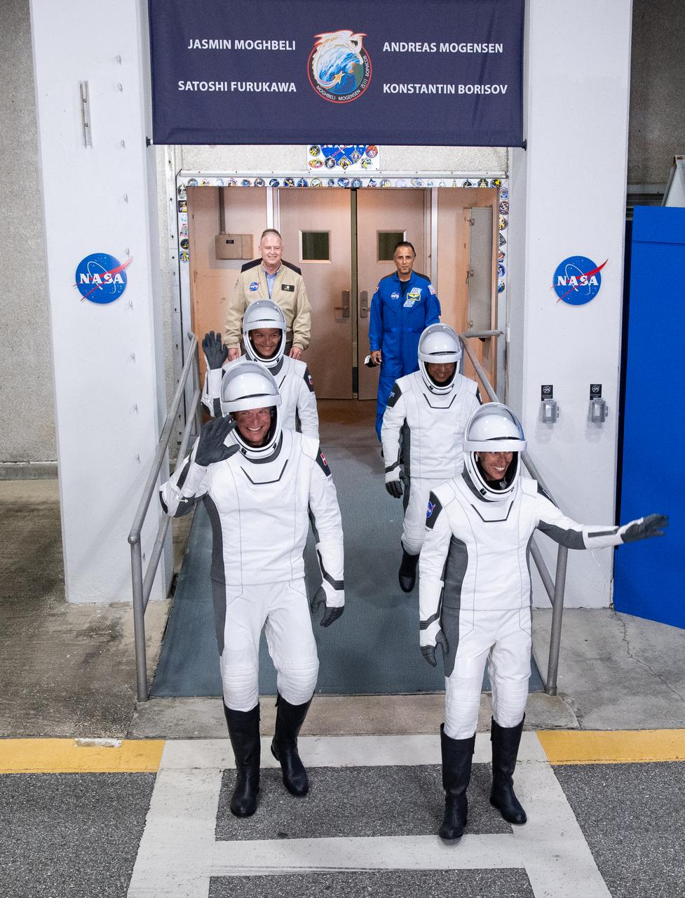 NASA astronaut Jasmin Moghbeli, right, ESA (European Space Agency) astronaut Andreas Mogensen, left, Japan Aerospace Exploration Agency (JAXA) astronaut Satoshi Furukawa, back right, and Roscosmos cosmonaut Konstantin Borisov, back left, wearing SpaceX spacesuits, are seen as they prepare to depart the Neil  A. Armstrong Operations and Checkout Building for Launch Complex 39A to board the SpaceX Dragon spacecraft for the Crew-7 mission launch, Friday, Aug. 25, 2023, at NASA’s Kennedy Space Center in Florida. NASA’s SpaceX Crew-7 mission is the seventh crew rotation mission of the SpaceX Crew Dragon spacecraft and Falcon 9 rocket to the International Space Station as part of the agency’s Commercial Crew Program. Moghbeli, Mogensen, Furukawa, and Borisov are scheduled to launch at 3:27 a.m. EDT, from Launch Complex 39A at the Kennedy Space Center.  Photo Credit: (NASA/Joel Kowsky)