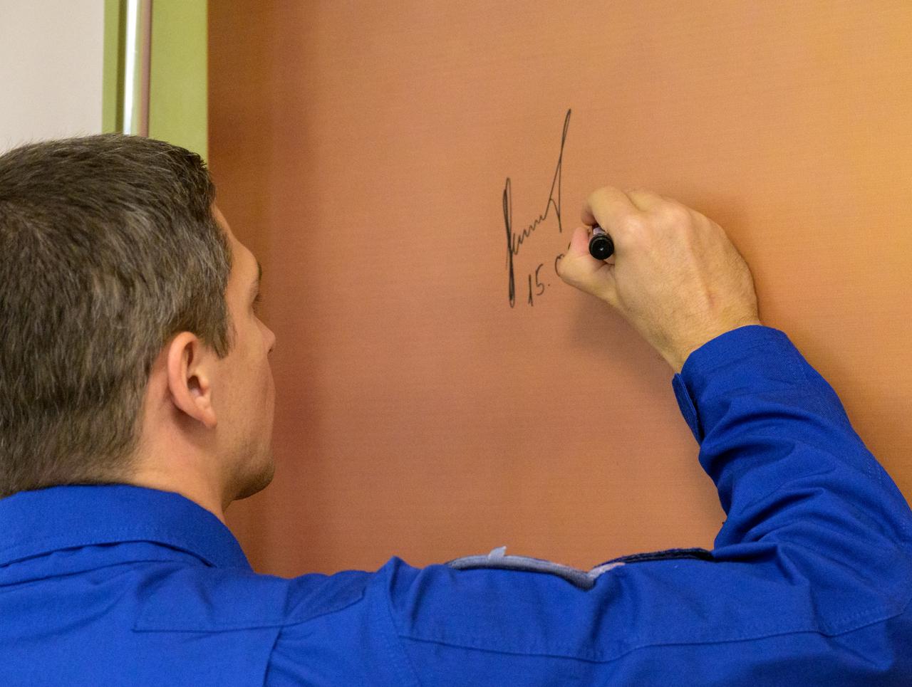 Expedition 70 Roscosmos cosmonaut Nikolai Chub signs a mural at the Cosmonaut Hotel prior to departing the hotel for launch on a Soyuz rocket with fellow crewmates NASA astronaut Loral O'Hara and Roscosmos cosmonaut Oleg Kononenko, Friday, Sept. 15, 2023, in Baikonur, Kazakhstan. The launch will send Expedition 70 NASA astronaut Loral O'Hara and Roscosmos cosmonauts Oleg Kononenko and Nikolai Chub on a mission to the International Space Station. Photo Credit: (NASA/Bill Ingalls)