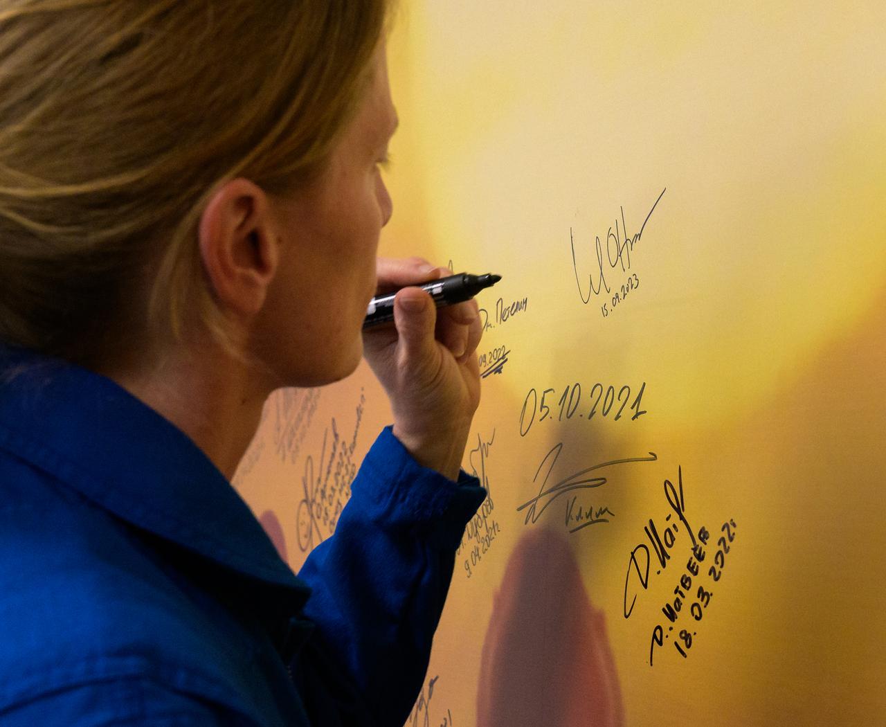 Expedition 70 NASA astronaut Loral O'Hara signs a mural at the Cosmonaut Hotel prior to departing the hotel for launch on a Soyuz rocket with fellow crewmates Roscosmos cosmonauts Oleg Kononenko and Nikolai Chub, Friday, Sept. 15, 2023, in Baikonur, Kazakhstan. The launch will send Expedition 70 NASA astronaut Loral O'Hara and Roscosmos cosmonauts Oleg Kononenko and Nikolai Chub on a mission to the International Space Station. Photo Credit: (NASA/Bill Ingalls)