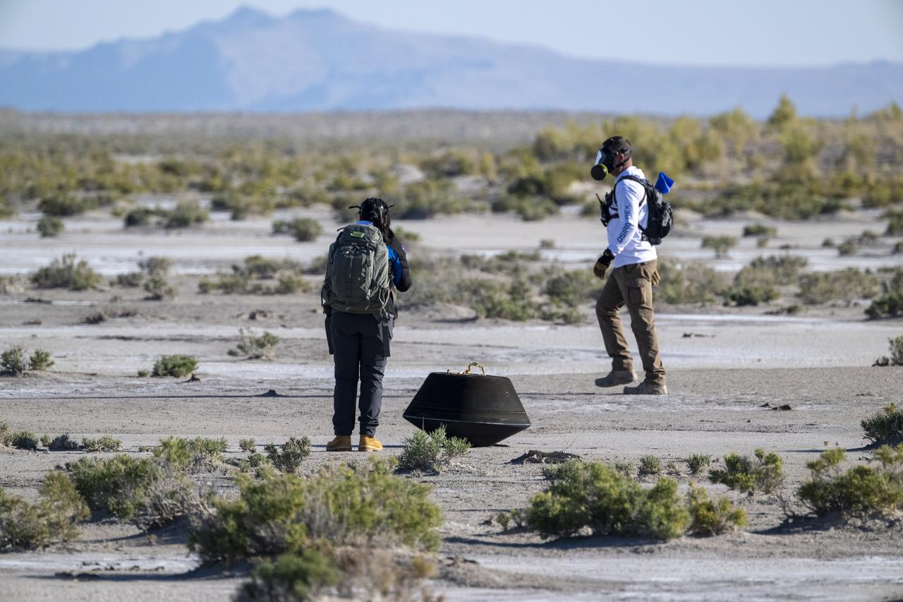 Lockheed Martin System Safety Engineer Victoria Thiem, left, and On Scene Commander of Recovery Stuart Wylie, right, perform preliminary checks on the sample return capsule from NASA’s OSIRIS-REx mission, Sunday, Sept. 24, 2023, shortly after the capsule landed at the Department of Defense's Utah Test and Training Range. The sample was collected from the asteroid Bennu in October 2020 by NASA’s OSIRIS-REx spacecraft. Photo Credit: (NASA/Keegan Barber)