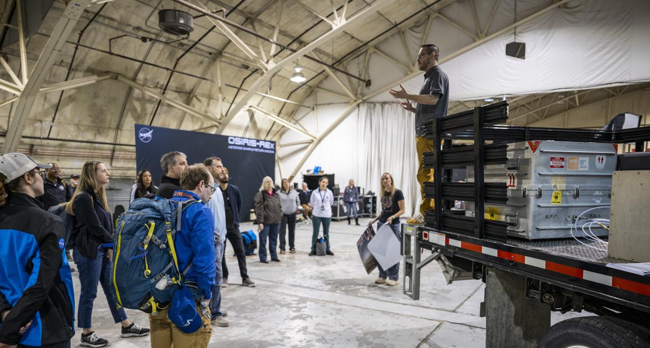 Lockheed Martin OSIRIS-REx Sample Return Capsule Ground Recovery Lead Richard Witherspoon, top right, delivers remarks to recovery and curation teams prior to loading a container with the science canister from NASA’s OSIRIS-REx mission onto a C-17 Globemaster aircraft, Monday, Sept. 25, 2023, at the Department of Defense's Utah Test and Training Range. The sample was collected from the asteroid Bennu in October 2020 by NASA’s OSIRIS-REx spacecraft. Photo Credit: (NASA/Keegan Barber)