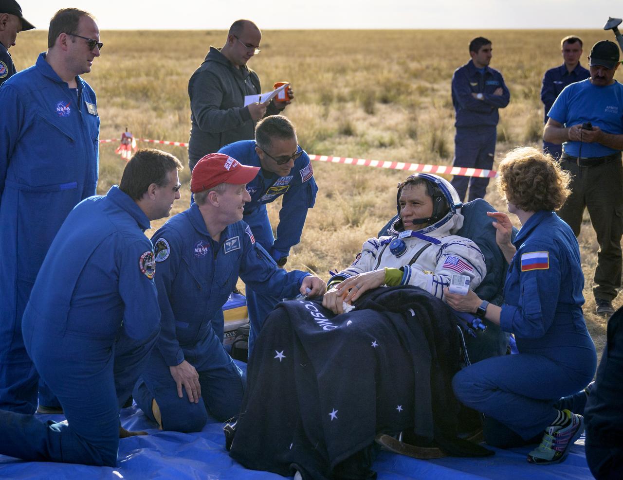 Expedition 69 NASA astronaut Frank Rubio is seen resting and talking with NASA ISS Program Manager Joel Montalbano, kneeling left, NASA Flight Surgeon Josef Schmid, red hat, and NASA Chief of the Astronaut Office Joe Acaba, outside the Soyuz MS-23 spacecraft after he landed with Roscosmos cosmonauts Sergey Prokopyev and Dmitri Petelin in a remote area near the town of Zhezkazgan, Kazakhstan on Wednesday, Sept. 27, 2023. The trio are returning to Earth after logging 371 days in space as members of Expeditions 68-69 aboard the International Space Station. For Rubio, his mission is the longest single spaceflight by a U.S. astronaut in history. Photo Credit: (NASA/Bill Ingalls)