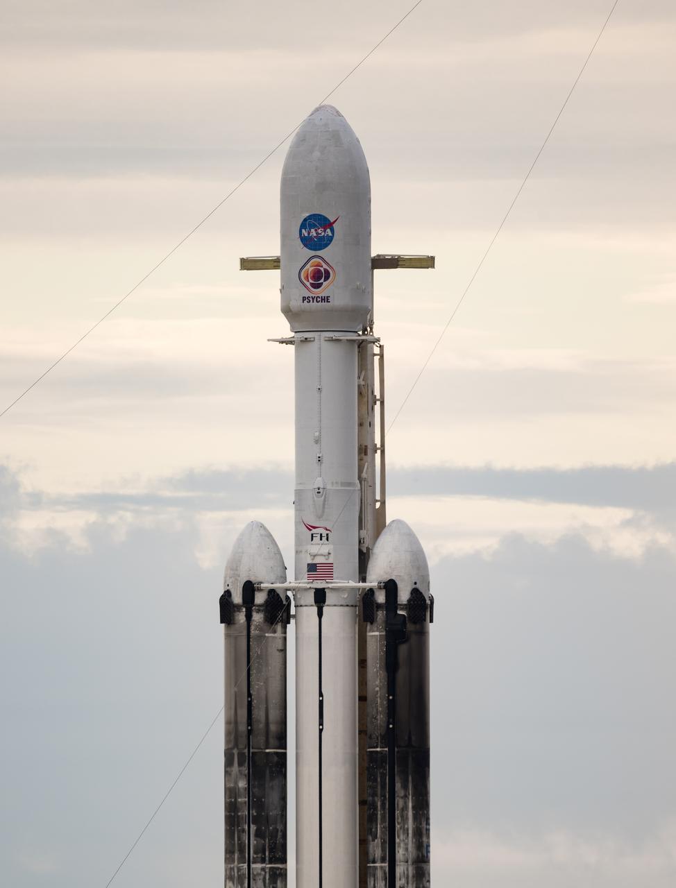 A SpaceX Falcon Heavy rocket with the Psyche spacecraft onboard is seen at Launch Complex 39A as preparations continue for the Psyche mission, Wednesday, Oct. 11, 2023, at NASA’s Kennedy Space Center in Florida. NASA’s Psyche spacecraft will travel to a metal-rich asteroid by the same name orbiting the Sun between Mars and Jupiter to study it’s composition. The spacecraft also carries the agency's Deep Space Optical Communications technology demonstration, which will test laser communications beyond the Moon. Photo Credit: (NASA/Aubrey Gemignani)