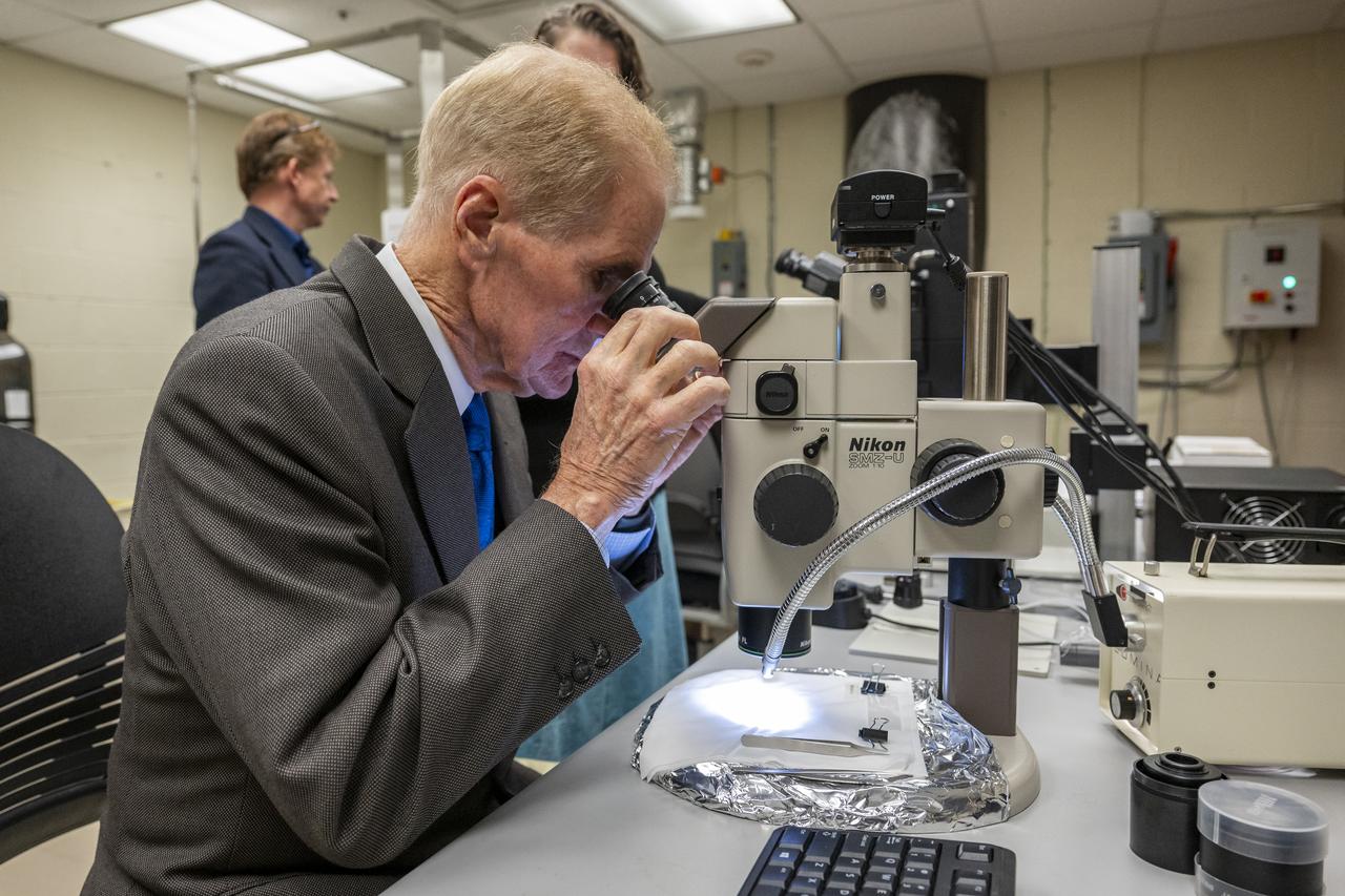 NASA Administrator Bill Nelson uses a microscope to view a sample from asteroid Bennu, Friday, Nov. 3, 2023, at the Smithsonian’s National Museum of Natural History in Washington. The sample was collected from the carbon rich near Earth asteroid Bennu in October 2020 by NASA’s OSIRIS-REx spacecraft.  Photo Credit: (NASA/Keegan Barber)