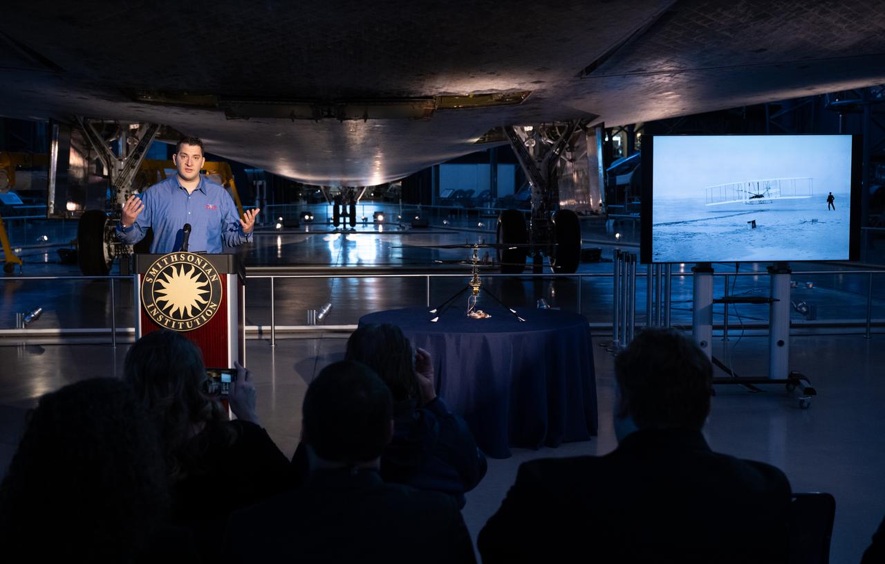 Teddy Tzanetos, Ingenuity project manager at NASA's Jet Propulsion Laboratory speaks at an event marking NASA’s donation of the aerial prototype of the Ingenuity Mars Helicopter, Friday, Dec. 15, 2023, at the Smithsonian National Air and Space Museum’s Steve F. Udvar-Hazy Center in Chantilly, Va. The aerial prototype of the Ingenuity Mars Helicopter, which was the first to demonstrate it was possible to fly in a simulated Mars environment at NASA’s Jet Propulsion Laboratory (JPL), was donated to the museum on Friday.  Photo Credit: (NASA/Joel Kowsky)