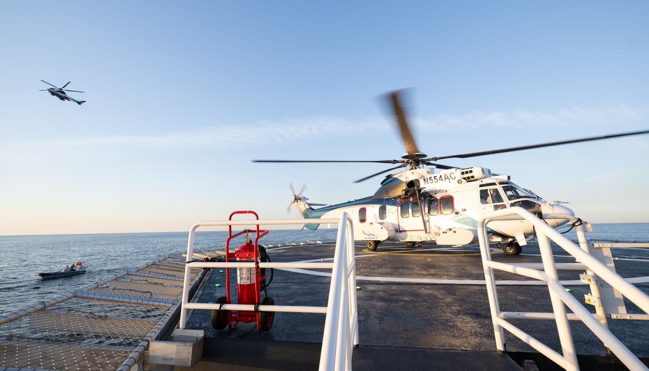 The helicopter carrying NASA astronaut Jasmin Moghbeli, ESA (European Space Agency) astronaut Andreas Mogensen, Japan Aerospace Exploration Agency (JAXA) astronaut Satoshi Furukawa, and Roscosmos cosmonaut Konstantin Borisov is seen as it prepares to take off from the SpaceX recovery ship MEGAN as a second helicopter that will carry cargo and support personnel back to shore flies past the ship in the Gulf of Mexico off the coast of Pensacola, Florida, Tuesday, March 12, 2024. Moghbeli, Mogensen, Furukawa, and Borisov are returning after nearly six-months in space as part of Expedition 70 aboard the International Space Station. Photo Credit: (NASA/Joel Kowsky)