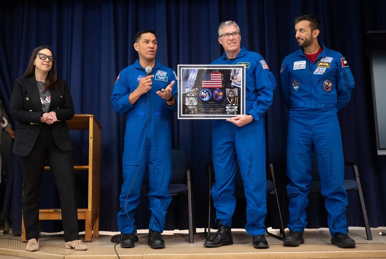 NASA astronauts Frank Rubio, second from left, and Stephen Bowen and UAE (United Arab Emirates) astronaut Sultan Alneyadi present a montage to Rolling Terrace Elementary School principal Rosa Mensah to be displayed at the school, Friday, March 22, 2024, in Takoma Park, Maryland. Bowen and Alneyadi spent 186 days aboard the International Space Station as part of Expedition 69; while Rubio set a new record for the longest single spaceflight by a U.S. astronaut, spending 371 days in orbit on an extended mission spanning Expeditions 68 and 69. Photo Credit: (NASA/Joel Kowsky)