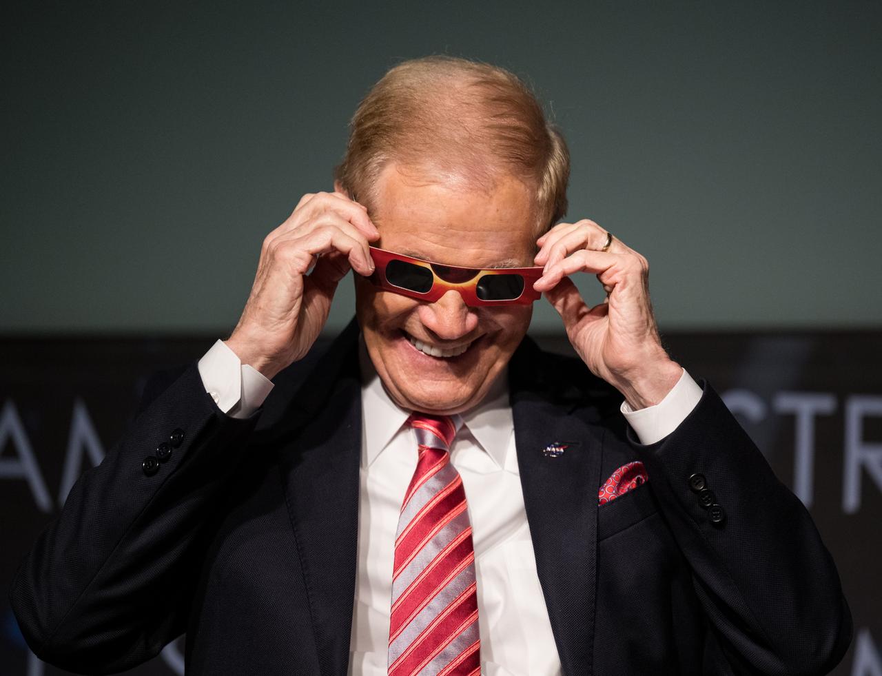 NASA Administrator Bill Nelson tries on some eclipse glasses at the conclusion of a media briefing to discuss the upcoming solar eclipse, Tuesday, March 26, 2024 at the Mary W. Jackson NASA Headquarters building in Washington. A total solar eclipse will sweep across a narrow portion of the North American continent from Mexico’s Pacific coast to the Atlantic coast of Newfoundland, Canada on April 8, 2024. A partial solar eclipse will be visible across the entire North American continent along with parts of Central America and Europe. Photo Credit: (NASA/Aubrey Gemignani)