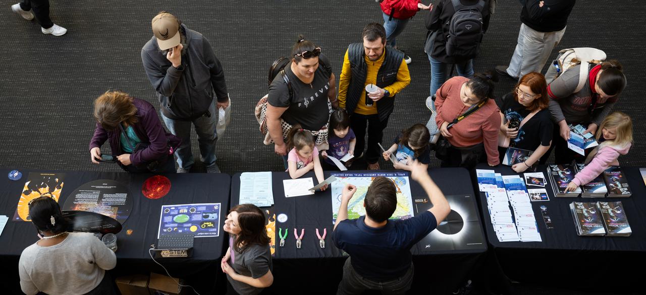 Visitors to The Children’s Museum of Indianapolis learn about the upcoming total solar eclipse from NASA staff, Saturday, April 6, 2024, in Indianapolis, Ind. On Monday, April 8, a total solar eclipse will sweep across a narrow portion of the North American continent from Mexico’s Pacific coast to the Atlantic coast of Newfoundland, Canada, while a partial solar eclipse will be visible across the entire North American continent along with parts of Central America and Europe. Photo Credit: (NASA/Joel Kowsky)
