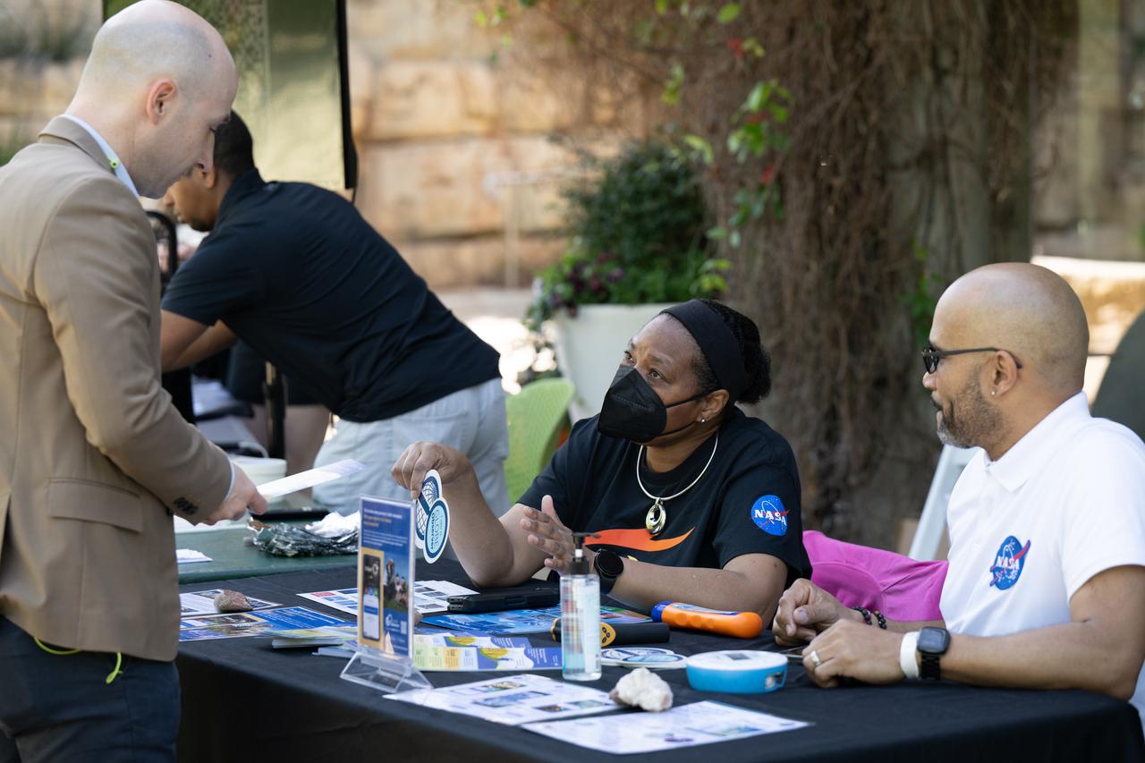 NASA Earth Science Education and Outreach Lead Dr. Trena Ferrell, second from right, hands out educational materials to guests at the Dallas Arboretum, Sunday, April 7, 2024, in Dallas, Texas. On Monday, April 8, a total solar eclipse will sweep across a narrow portion of the North American continent from Mexico’s Pacific coast to the Atlantic coast of Newfoundland, Canada, while a partial solar eclipse will be visible across the entire North American continent along with parts of Central America and Europe. Photo Credit: (NASA/Keegan Barber)