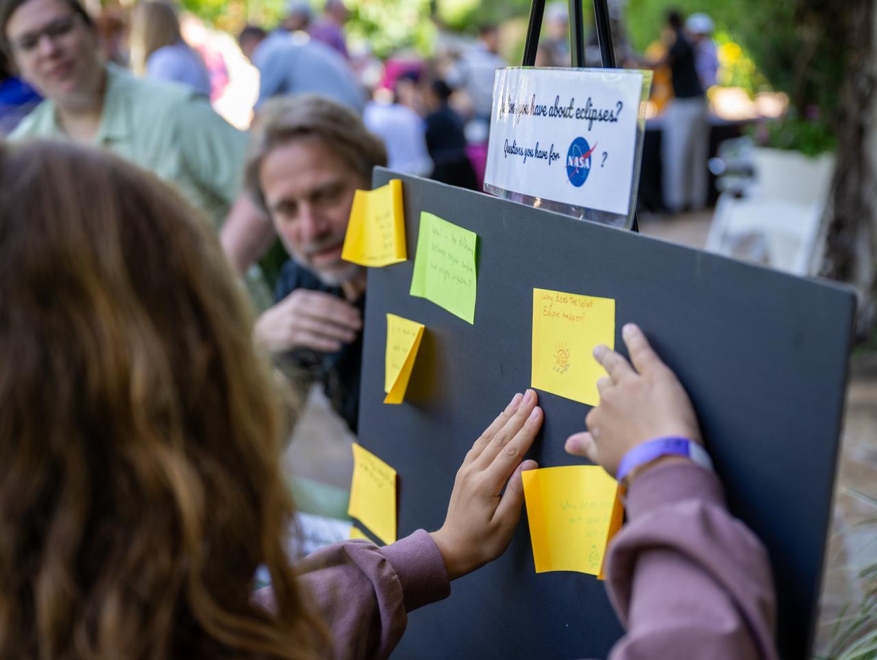 Guests place their questions about the solar eclipse upon a board at the Dallas Arboretum, Sunday, April 7, 2024, in Dallas, Texas. On Monday, April 8, a total solar eclipse will sweep across a narrow portion of the North American continent from Mexico’s Pacific coast to the Atlantic coast of Newfoundland, Canada, while a partial solar eclipse will be visible across the entire North American continent along with parts of Central America and Europe. Photo Credit: (NASA/Keegan Barber)
