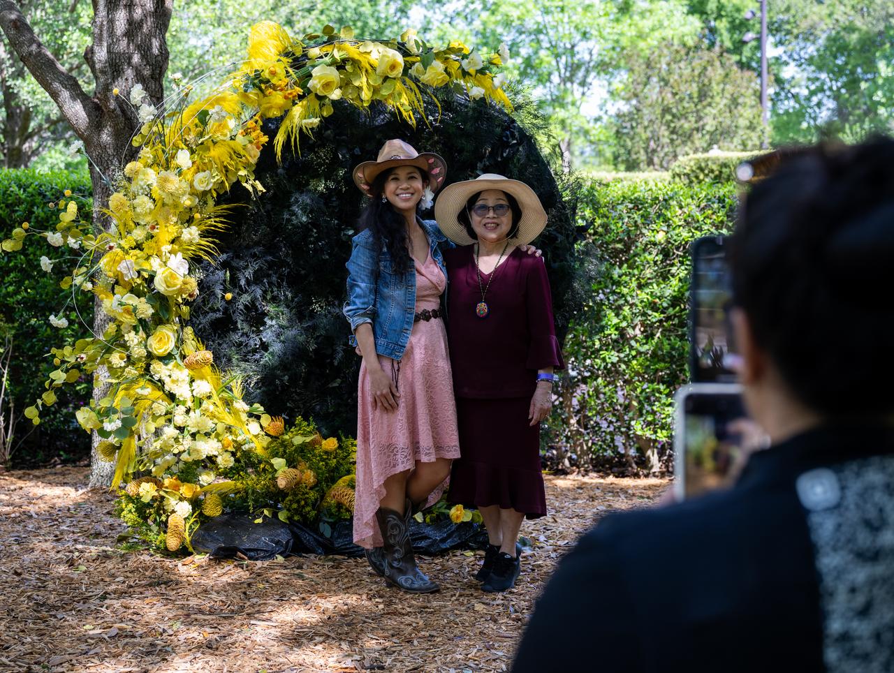 Guests pose for a photo in front of a floral solar eclipse display at the Dallas Arboretum, Sunday, April 7, 2024, in Dallas, Texas. On Monday, April 8, a total solar eclipse will sweep across a narrow portion of the North American continent from Mexico’s Pacific coast to the Atlantic coast of Newfoundland, Canada, while a partial solar eclipse will be visible across the entire North American continent along with parts of Central America and Europe. Photo Credit: (NASA/Keegan Barber)