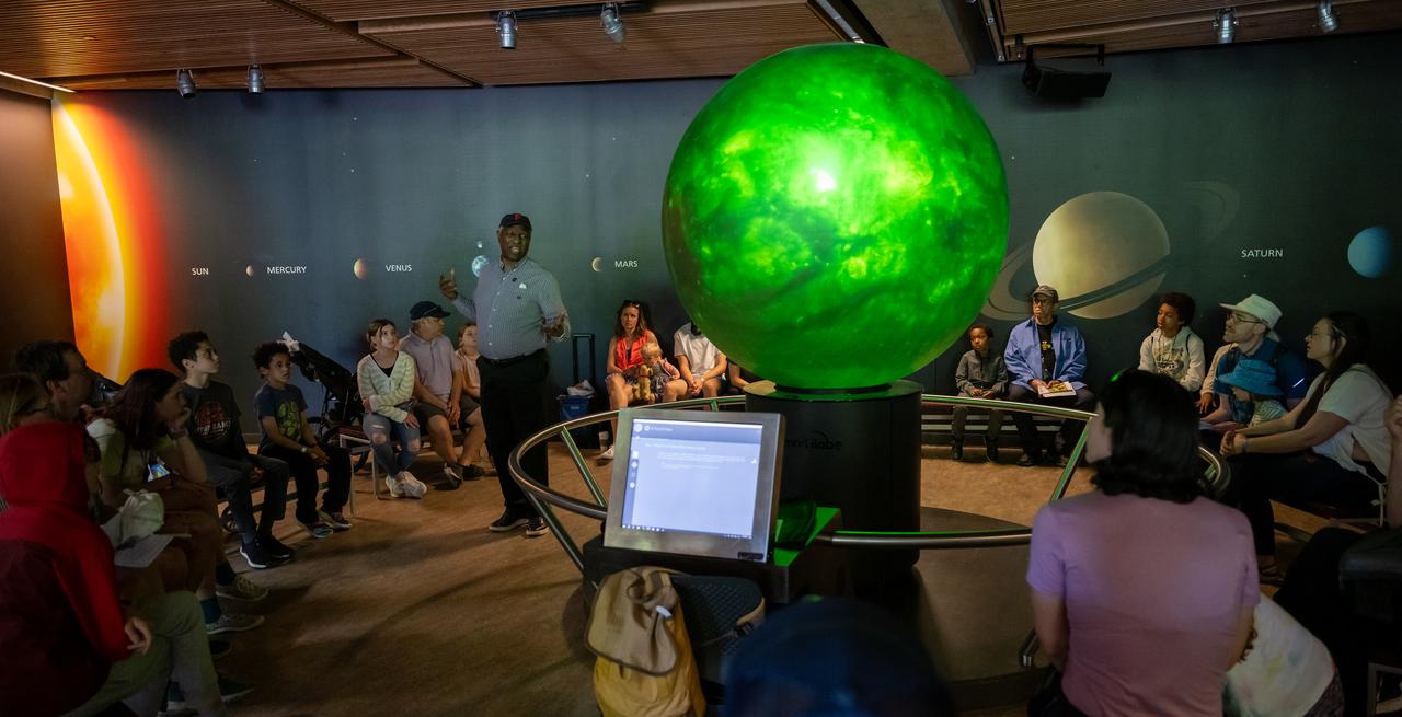 Maurice Henderson speaks to guests about the upcoming total solar eclipse at the Dallas Arboretum, Sunday, April 7, 2024, in Dallas, Texas. On Monday, April 8, a total solar eclipse will sweep across a narrow portion of the North American continent from Mexico’s Pacific coast to the Atlantic coast of Newfoundland, Canada, while a partial solar eclipse will be visible across the entire North American continent along with parts of Central America and Europe. Photo Credit: (NASA/Keegan Barber)