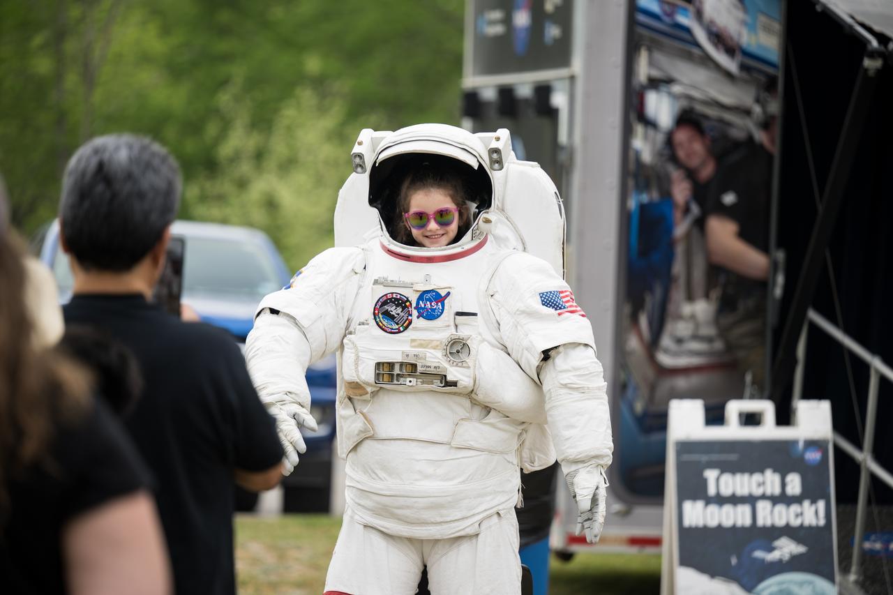 People are seen posing for photos behind a spacesuit as they prepare to watch a total solar eclipse in Kerrville, TX on Monday, April 8, 2024. A total solar eclipse swept across a narrow portion of the North American continent from Mexico’s Pacific coast to the Atlantic coast of Newfoundland, Canada. A partial solar eclipse was visible across the entire North American continent along with parts of Central America and Europe.  Photo Credit: (NASA/Aubrey Gemignani)