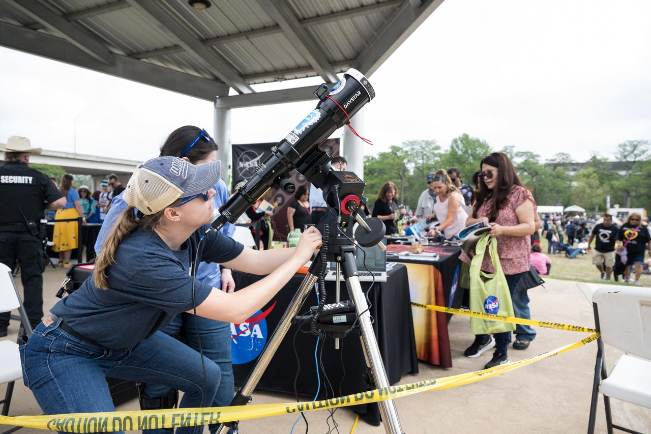 Guests visit NASA tables as NASA staff operate a telescope during the solar eclipse in Kerrville, TX on Monday, April 8, 2024. A total solar eclipse swept across a narrow portion of the North American continent from Mexico’s Pacific coast to the Atlantic coast of Newfoundland, Canada. A partial solar eclipse was visible across the entire North American continent along with parts of Central America and Europe.  Photo Credit: (NASA/Aubrey Gemignani)