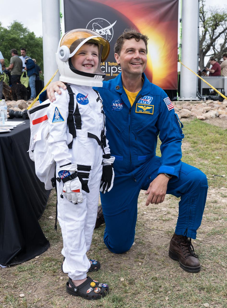 Astronaut Reid Wiseman poses for a photo with a guest dressed as an astronaut at the Kerrville eclipse festival in Kerrville, TX on Monday, April 8, 2024. A total solar eclipse swept across a narrow portion of the North American continent from Mexico’s Pacific coast to the Atlantic coast of Newfoundland, Canada. A partial solar eclipse was visible across the entire North American continent along with parts of Central America and Europe.  Photo Credit: (NASA/Aubrey Gemignani)