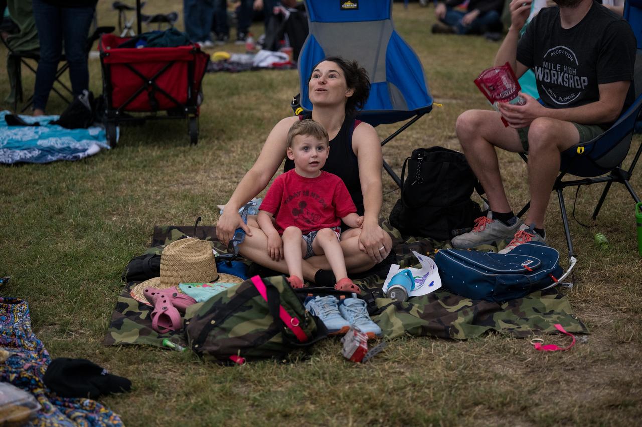 People are seen as they watch a total solar eclipse through protective glasses in Kerrville, TX on Monday, April 8, 2024. A total solar eclipse swept across a narrow portion of the North American continent from Mexico’s Pacific coast to the Atlantic coast of Newfoundland, Canada. A partial solar eclipse was visible across the entire North American continent along with parts of Central America and Europe.  Photo Credit: (NASA/Aubrey Gemignani)