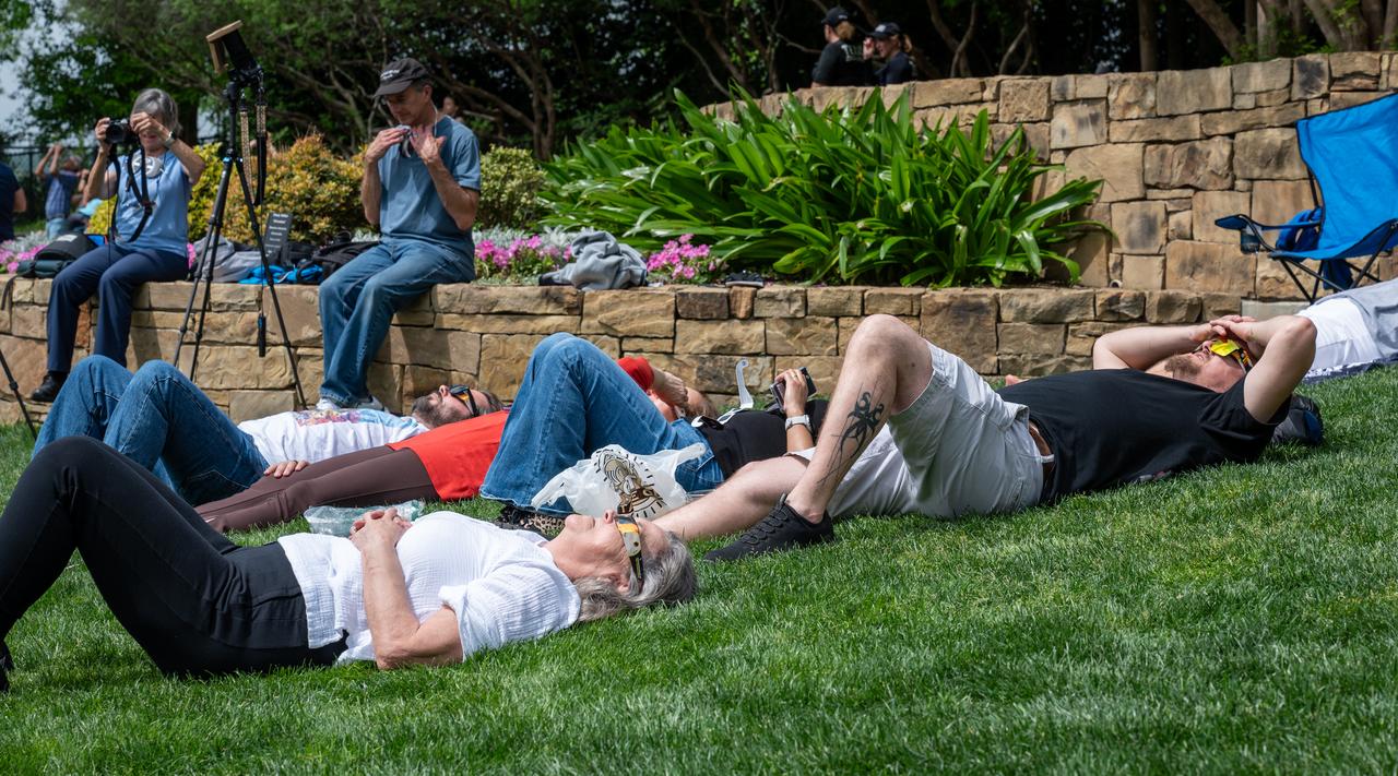 People are seen as they watch a total solar eclipse in Dallas, Texas on Monday, April 8, 2024. A total solar eclipse swept across a narrow portion of the North American continent from Mexico’s Pacific coast to the Atlantic coast of Newfoundland, Canada. A partial solar eclipse was visible across the entire North American continent along with parts of Central America and Europe. Photo Credit: (NASA/Keegan Barber)