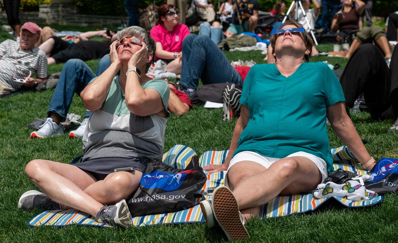 People are seen as they watch a total solar eclipse in Dallas, Texas on Monday, April 8, 2024. A total solar eclipse swept across a narrow portion of the North American continent from Mexico’s Pacific coast to the Atlantic coast of Newfoundland, Canada. A partial solar eclipse was visible across the entire North American continent along with parts of Central America and Europe. Photo Credit: (NASA/Keegan Barber)