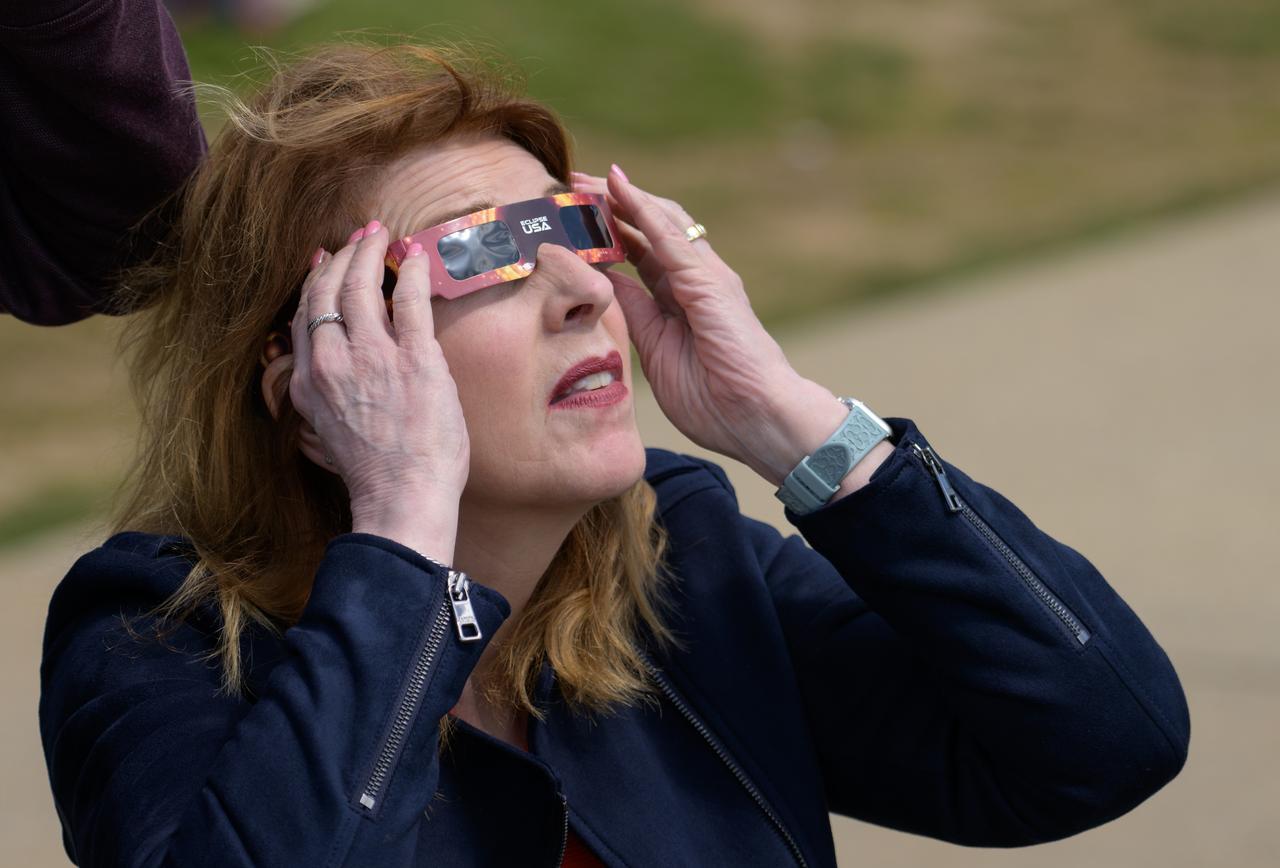 A woman watches a partial solar eclipse through protective glasses in Washington, on Monday, April 8, 2024. A total solar eclipse swept across a narrow portion of the North American continent from Mexico’s Pacific coast to the Atlantic coast of Newfoundland, Canada. A partial solar eclipse was visible across the entire North American continent along with parts of Central America and Europe.  Photo Credit: (NASA/Bill Ingalls)