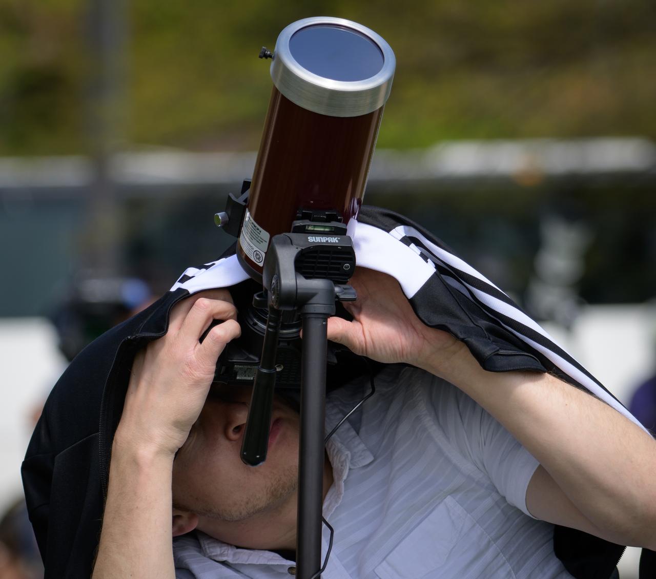 A man views a partial solar eclipse through a telescope equipped with a protective solar filter in Washington, on Monday, April 8, 2024. A total solar eclipse swept across a narrow portion of the North American continent from Mexico’s Pacific coast to the Atlantic coast of Newfoundland, Canada. A partial solar eclipse was visible across the entire North American continent along with parts of Central America and Europe.  Photo Credit: (NASA/Bill Ingalls)