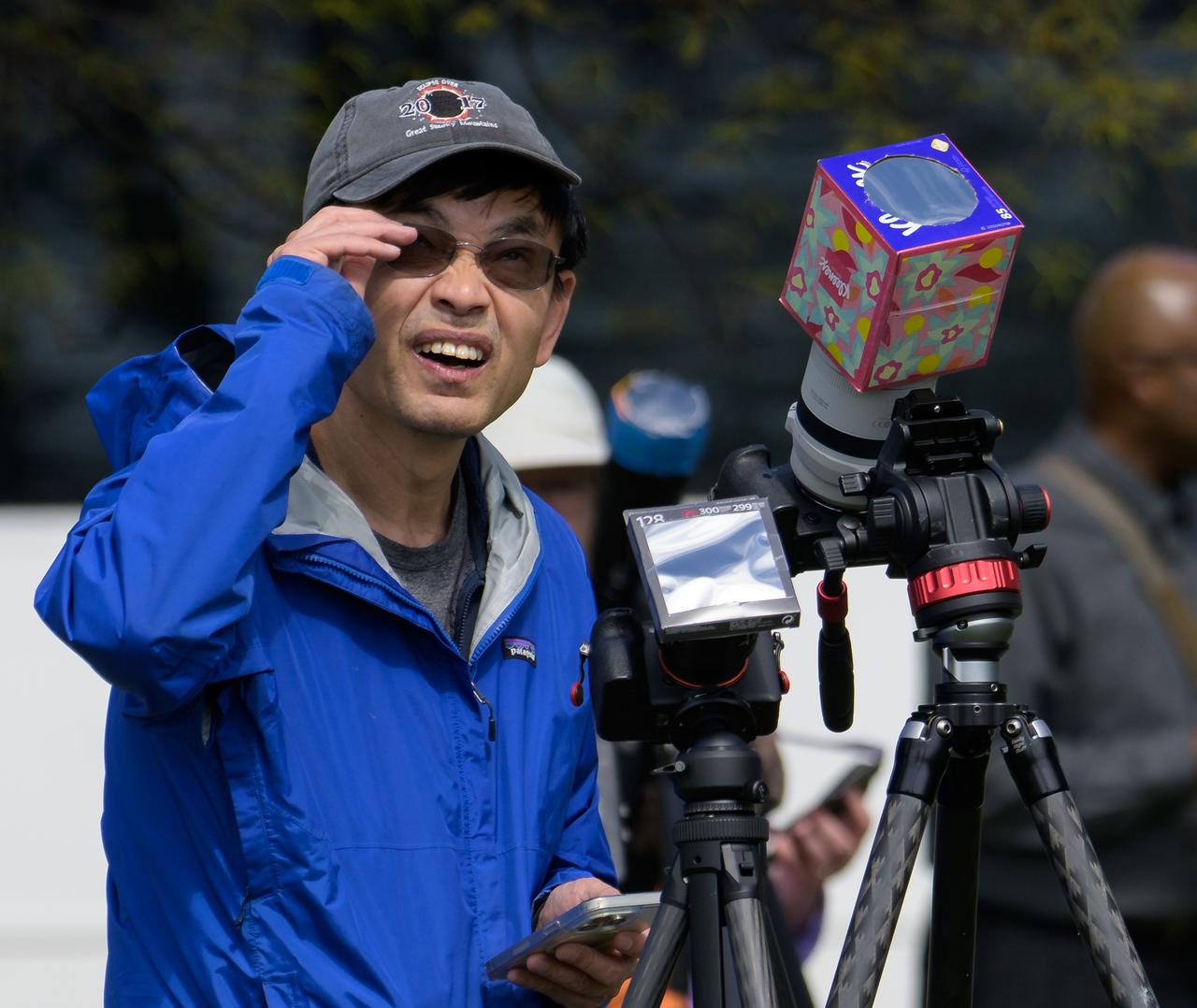 A man monitors his cameras during a partial solar eclipse in Washington, on Monday, April 8, 2024. A total solar eclipse swept across a narrow portion of the North American continent from Mexico’s Pacific coast to the Atlantic coast of Newfoundland, Canada. A partial solar eclipse was visible across the entire North American continent along with parts of Central America and Europe.  Photo Credit: (NASA/Bill Ingalls)