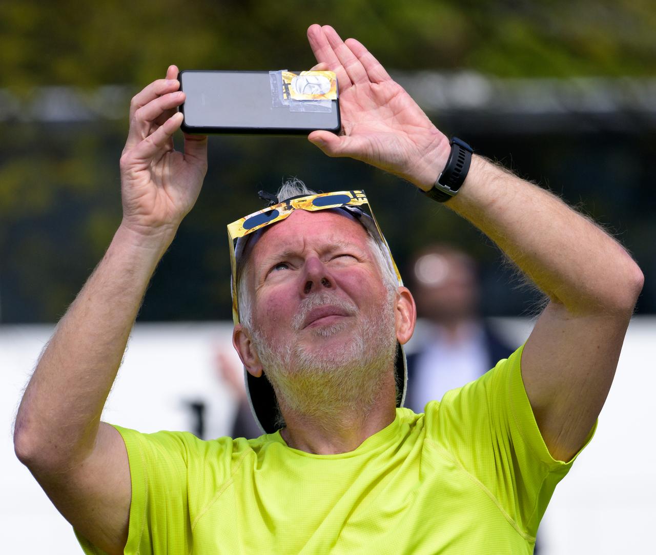 A man uses his smart phone to photograph a partial solar eclipse in Washington, on Monday, April 8, 2024. A total solar eclipse swept across a narrow portion of the North American continent from Mexico’s Pacific coast to the Atlantic coast of Newfoundland, Canada. A partial solar eclipse was visible across the entire North American continent along with parts of Central America and Europe.  Photo Credit: (NASA/Bill Ingalls)