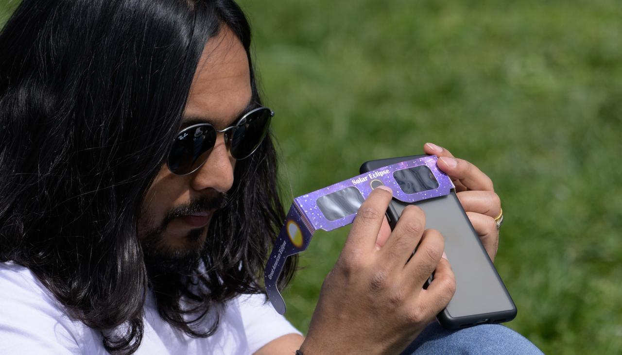 A man uses his smart phone to photograph a partial solar eclipse in Washington, on Monday, April 8, 2024. A total solar eclipse swept across a narrow portion of the North American continent from Mexico’s Pacific coast to the Atlantic coast of Newfoundland, Canada. A partial solar eclipse was visible across the entire North American continent along with parts of Central America and Europe.  Photo Credit: (NASA/Bill Ingalls)