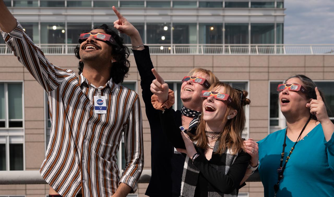 People gather on the roof of NASA Headquarters in Washington to watch a partial solar eclipse through protective glasses in Washington, on Monday, April 8, 2024. A total solar eclipse swept across a narrow portion of the North American continent from Mexico’s Pacific coast to the Atlantic coast of Newfoundland, Canada. A partial solar eclipse was visible across the entire North American continent along with parts of Central America and Europe. Photo Credit: (NASA/Connie Moore)