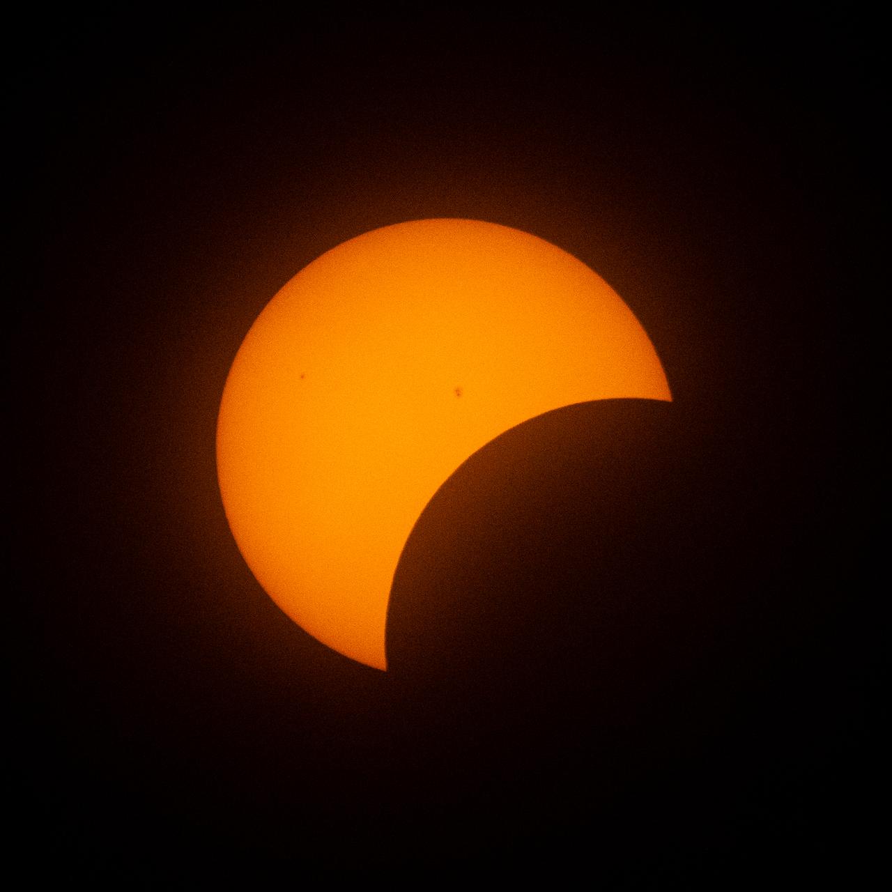 The Moon is seen passing in front of the Sun during a partial solar eclipse from the Indianapolis Motor Speedway, Monday, April 8, 2024, in Indianapolis, Indiana. A total solar eclipse swept across a narrow portion of the North American continent from Mexico’s Pacific coast to the Atlantic coast of Newfoundland, Canada. A partial solar eclipse was visible across the entire North American continent along with parts of Central America and Europe.  Photo Credit: (NASA/Joel Kowsky)