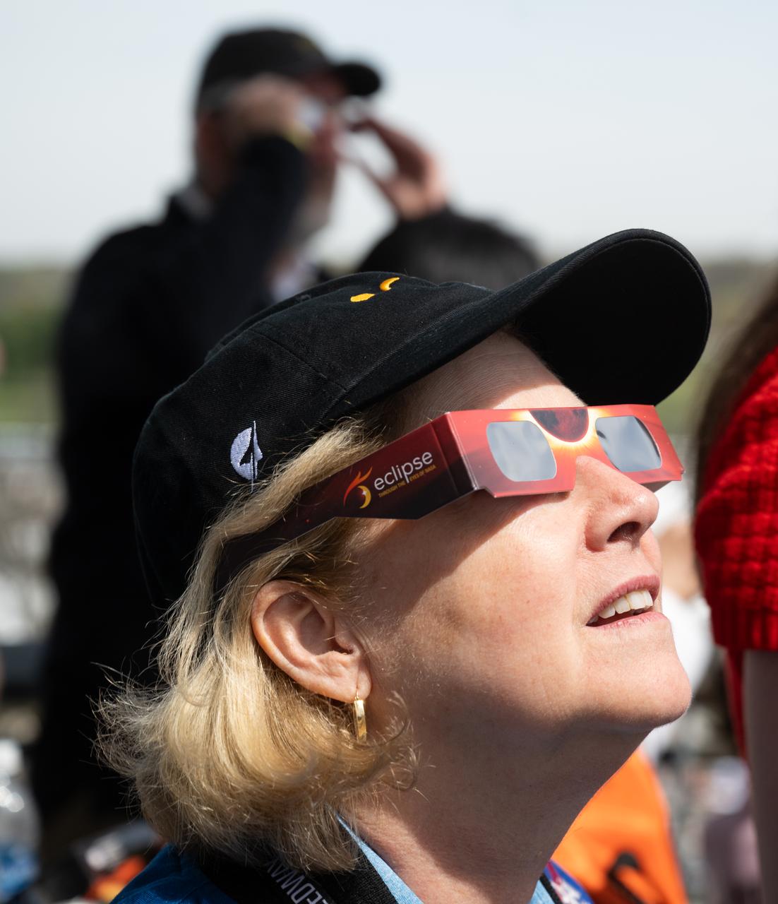 NASA Deputy Administrator Pam Melroy is seen as she watchs a total solar eclipse through protective glasses at the Indianapolis Motor Speedway, Monday, April 8, 2024, in Indianapolis, Indiana. A total solar eclipse swept across a narrow portion of the North American continent from Mexico’s Pacific coast to the Atlantic coast of Newfoundland, Canada. A partial solar eclipse was visible across the entire North American continent along with parts of Central America and Europe.  Photo Credit: (NASA/Joel Kowsky)