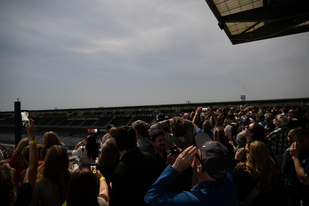 People are seen as they watch a total solar eclipse at the Indianapolis Motor Speedway, Monday, April 8, 2024, in Indianapolis, Indiana. A total solar eclipse swept across a narrow portion of the North American continent from Mexico’s Pacific coast to the Atlantic coast of Newfoundland, Canada. A partial solar eclipse was visible across the entire North American continent along with parts of Central America and Europe.  Photo Credit: (NASA/Joel Kowsky)