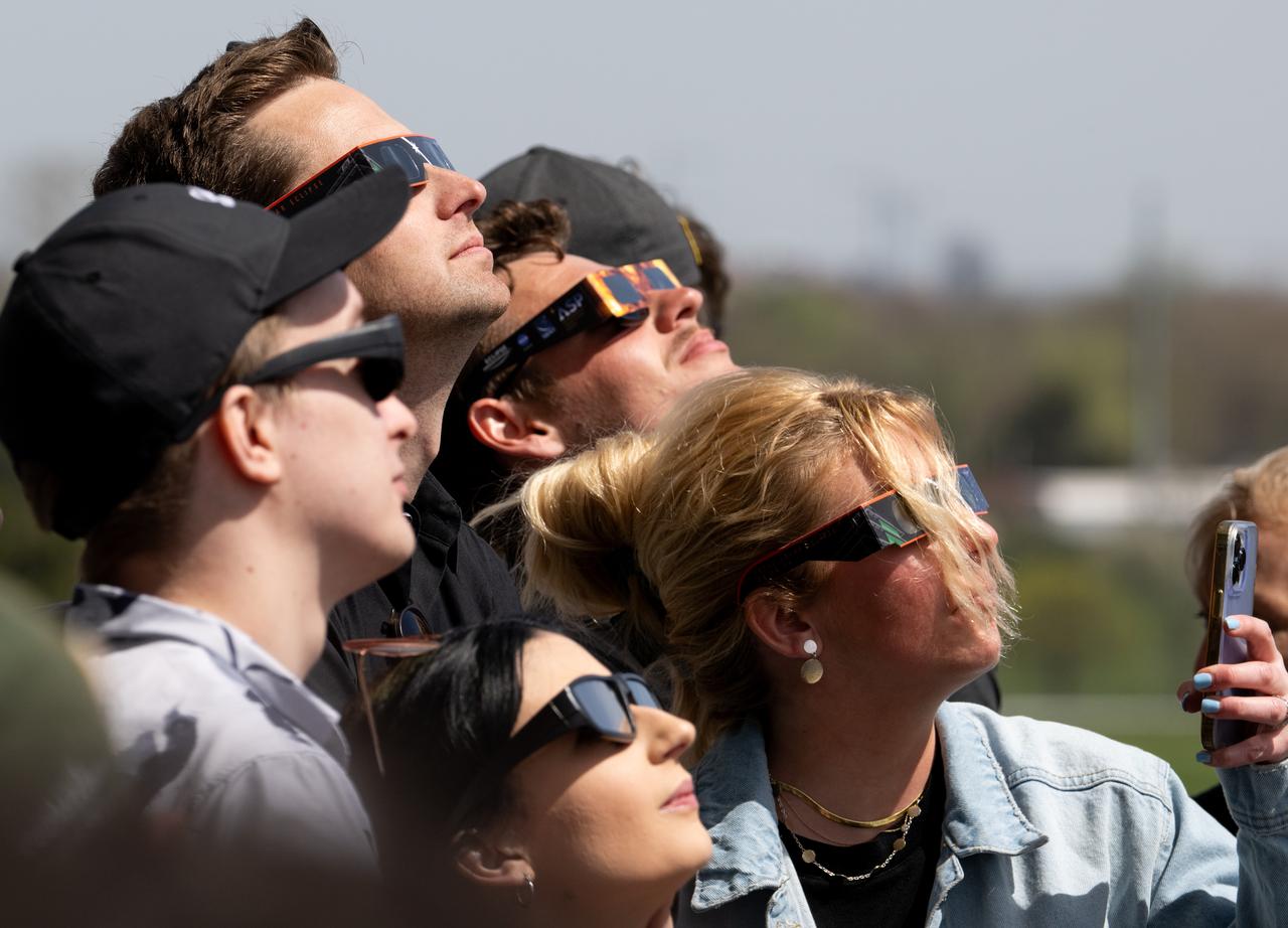 People are seen as they watch a total solar eclipse through protective glasses at the Indianapolis Motor Speedway, Monday, April 8, 2024, in Indianapolis, Indiana. A total solar eclipse swept across a narrow portion of the North American continent from Mexico’s Pacific coast to the Atlantic coast of Newfoundland, Canada. A partial solar eclipse was visible across the entire North American continent along with parts of Central America and Europe.  Photo Credit: (NASA/Joel Kowsky)