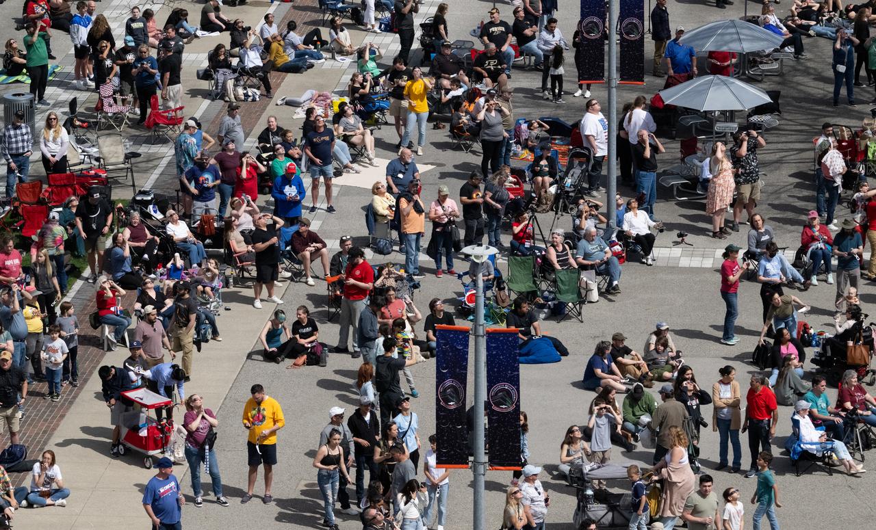 Attendees are seen on Pagoda Plaza as they watch the progression of a total solar eclipse from the Indianapolis Motor Speedway, Monday, April 8, 2024, in Indianapolis, Indiana. A total solar eclipse swept across a narrow portion of the North American continent from Mexico’s Pacific coast to the Atlantic coast of Newfoundland, Canada. A partial solar eclipse was visible across the entire North American continent along with parts of Central America and Europe.  Photo Credit: (NASA/Joel Kowsky)