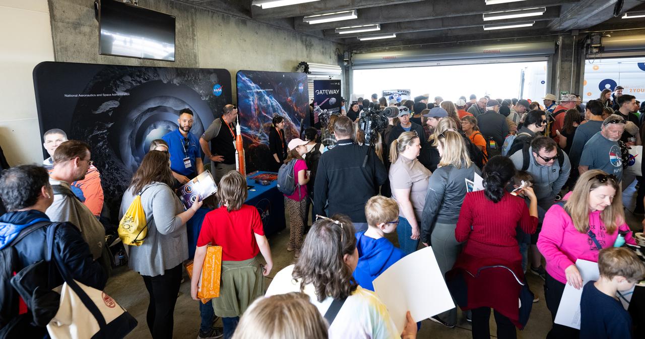 Attendees at the Indianapolis Motor Speedway view NASA exhibits ahead of the total solar eclipse, Monday, April 8, 2024, in Indianapolis, Ind. A total solar eclipse swept across a narrow portion of the North American continent from Mexico’s Pacific coast to the Atlantic coast of Newfoundland, Canada. A partial solar eclipse was visible across the entire North American continent along with parts of Central America and Europe.  Photo Credit: (NASA/Joel Kowsky)