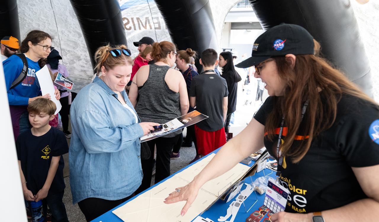 Attendees at the Indianapolis Motor Speedway view NASA exhibits ahead of the total solar eclipse, Monday, April 8, 2024, in Indianapolis, Ind. A total solar eclipse swept across a narrow portion of the North American continent from Mexico’s Pacific coast to the Atlantic coast of Newfoundland, Canada. A partial solar eclipse was visible across the entire North American continent along with parts of Central America and Europe.  Photo Credit: (NASA/Joel Kowsky)
