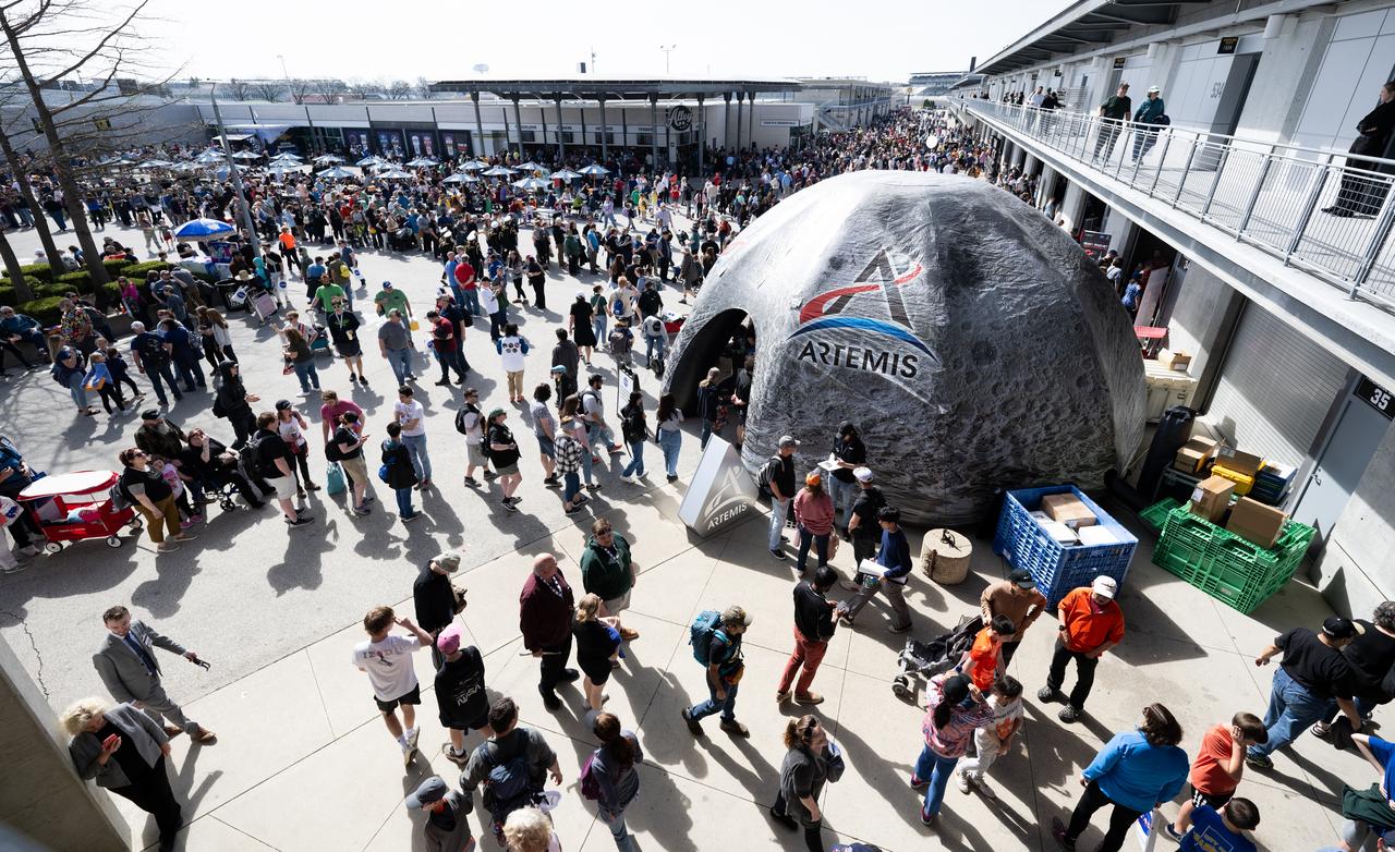 Attendees at the Indianapolis Motor Speedway view NASA exhibits ahead of the total solar eclipse, Monday, April 8, 2024, in Indianapolis, Ind. A total solar eclipse swept across a narrow portion of the North American continent from Mexico’s Pacific coast to the Atlantic coast of Newfoundland, Canada. A partial solar eclipse was visible across the entire North American continent along with parts of Central America and Europe.  Photo Credit: (NASA/Joel Kowsky)
