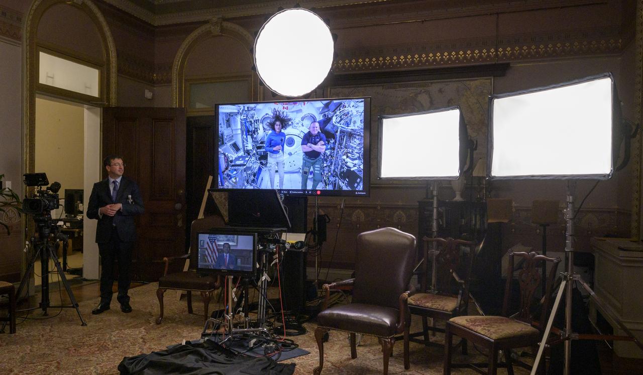 Daniel Evans, NASA's Director of Civil Space Policy standing left, looks on as NASA’s Boeing Crew Flight Test crew members Suni Williams, left, and Butch Wilmore are seen aboard the International Space Station on a monitor during an Earth-to-space call with Chirag Parikh, Deputy Assistant to the President and Executive Secretary of the National Space Council, Monday, June 10, 2024 at the Eisenhower Executive Office Building in Washington. Parikh spoke to Williams and Wilmore about their mission aboard Boeing’s Starliner Spacecraft. Photo Credit: (NASA/Bill Ingalls)