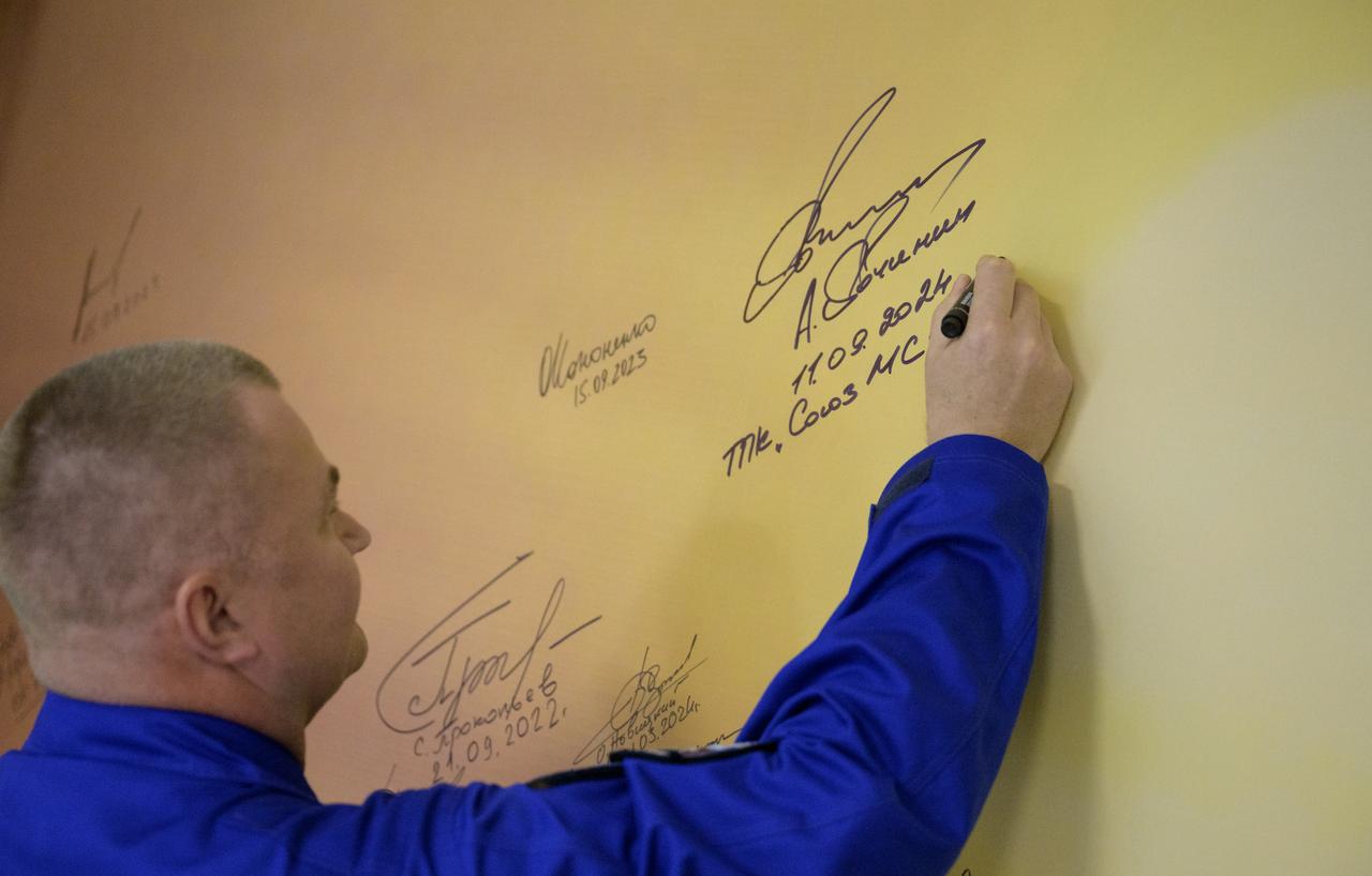 Roscosmos cosmonaut Alexey Ovchinin signs a mural at the Cosmonaut Hotel prior to departing for suit-up and launch on a Soyuz rocket with fellow crew mates, Roscosmos cosmonaut Ivan Vagner, and NASA astronaut Don Pettit, Wednesday, Sept. 11, 2024, in Baikonur, Kazakhstan. The launch will send Pettit, Ovchinin, Vagner, on a mission to the International Space Station. Photo Credit: (NASA/Bill Ingalls)