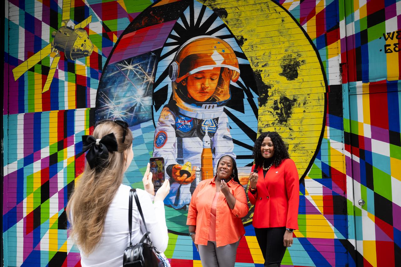 Michelle Jones, NASA’s deputy associate administrator for communications, left, and Aya Collins, director of the engagement division of NASA’s Office of Communications, record a video for social media in front of the mural “To the Moon, and Back” by the New York-based artist team Geraluz and WERC that was created as part of the reimagined NASA Art Program, Tuesday, September 24, 2024, in New York City’s Hudson Square neighborhood. For the inaugural project of the reestablished NASA Art Program the agency collaborated with the Hudson Square Business Improvement District on an open call for New York-based artists to design and install a large-scale mural inspired by NASA’s work and missions. Photo Credit: (NASA/Joel Kowsky)