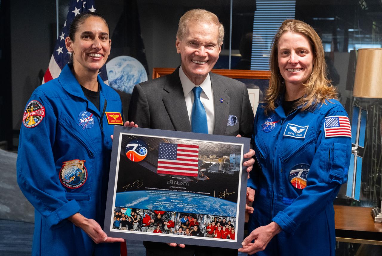 NASA astronauts Jasmin Moghbeli, left, and Loral O’Hara, right, pose for a picture with NASA Administrator Bill Nelson after presenting him with a montage from their mission to the International Space Station, Wednesday, Dec. 4, 2024 at the Mary W. Jackson NASA Headquarters Building in Washington. O’Hara and Moghbeli spent six months in space as part of Expedition 70 aboard the International Space Station.  Photo Credit: (NASA/Joel Kowsky)