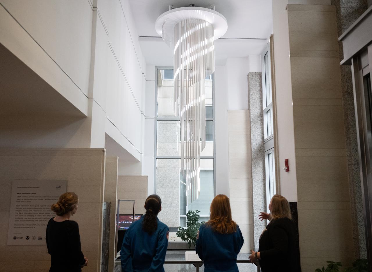Eleanor Stokes, program manager for NASA’s Earth Information Center, left, and Nicole Ramberg-Pihl, project manager for NASA’s Earth Information Center, right, speak with NASA astronauts Jasmin Moghbeli, second from left, and Loral O’Hara, second from right, during a tour of the Earth Information Center, Wednesday, Dec. 4, 2024, at the Mary W. Jackson NASA Headquarters Building in Washington. O’Hara and Moghbeli spent six months in space as part of Expedition 70 aboard the International Space Station.  Photo Credit: (NASA/Joel Kowsky)