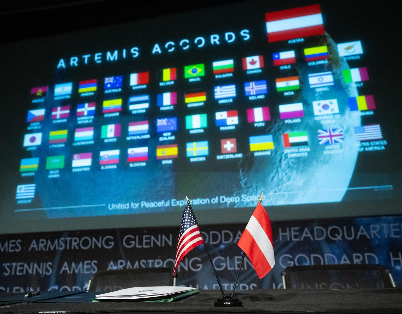 The flags of the United States and the Republic of Austria are seen before an Artemis Accords signing ceremony, Wednesday, Dec. 11, 2024, at the Mary W. Jackson NASA Headquarters building in Washington. The Republic of Austria is the 50th country to sign the Artemis Accords, which establish a practical set of principles to guide space exploration cooperation among nations participating in NASA’s Artemis program.  Photo Credit: (NASA/Joel Kowsky)
