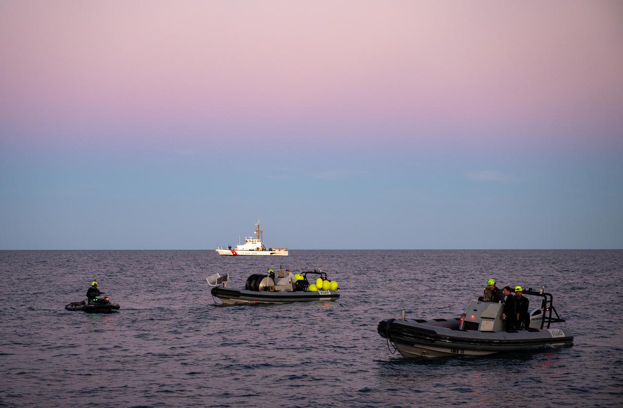 A United States Coast Guard vessel and SpaceX fast boat teams are seen shortly after the landing of a SpaceX Dragon spacecraft with NASA astronauts Nick Hague, Suni Williams, Butch Wilmore, and Roscosmos cosmonaut Aleksandr Gorbunov aboard, Tuesday, March 18, 2025, off the coast of Tallahassee, Florida. Hague, Gorbunov, Williams, and Wilmore are returning from a long-duration science expedition aboard the International Space Station. Photo Credit: (NASA/Keegan Barber)
