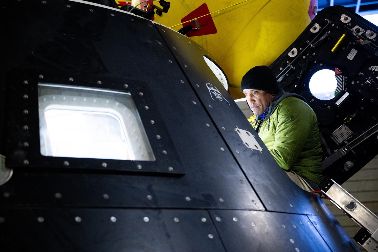 NASA astronaut and Artemis II pilot Victor Glover is seen in the hatch of the Crew Module Test Article (CMTA), a full-scale replica of the Orion spacecraft, during a familiarization walkthrough as part of Underway Recovery Test-12 onboard USS Somerset, Tuesday, March 25, 2025. During the test, NASA and Department of Defense teams are practicing to ensure recovery procedures are validated as NASA plans to send the Artemis II astronauts around the Moon and splashdown in the Pacific Ocean. Photo Credit: (NASA/Joel Kowsky)