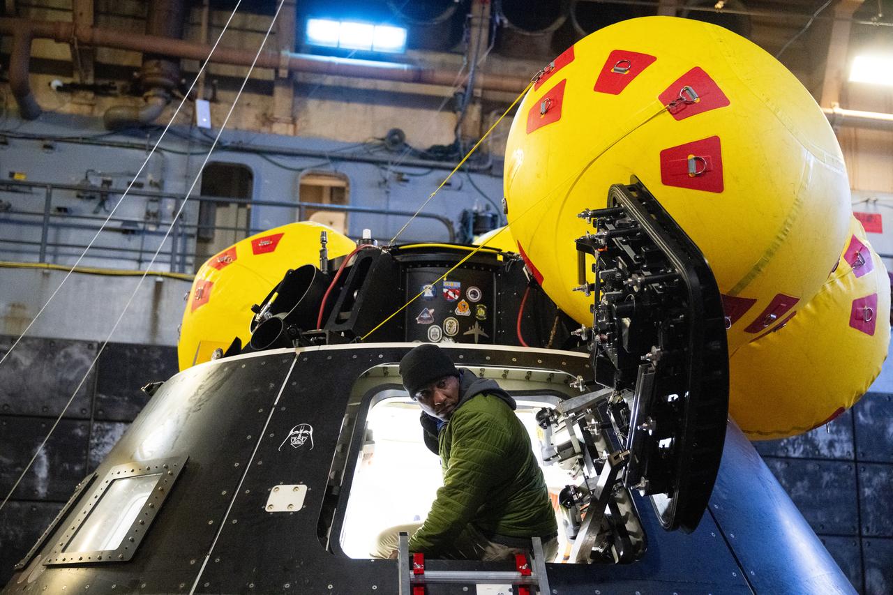 NASA astronaut and Artemis II pilot Victor Glover is seen in the hatch of the Crew Module Test Article (CMTA), a full-scale replica of the Orion spacecraft, during a familiarization walkthrough as part of Underway Recovery Test-12 onboard USS Somerset, Tuesday, March 25, 2025. During the test, NASA and Department of Defense teams are practicing to ensure recovery procedures are validated as NASA plans to send the Artemis II astronauts around the Moon and splashdown in the Pacific Ocean. Photo Credit: (NASA/Joel Kowsky)