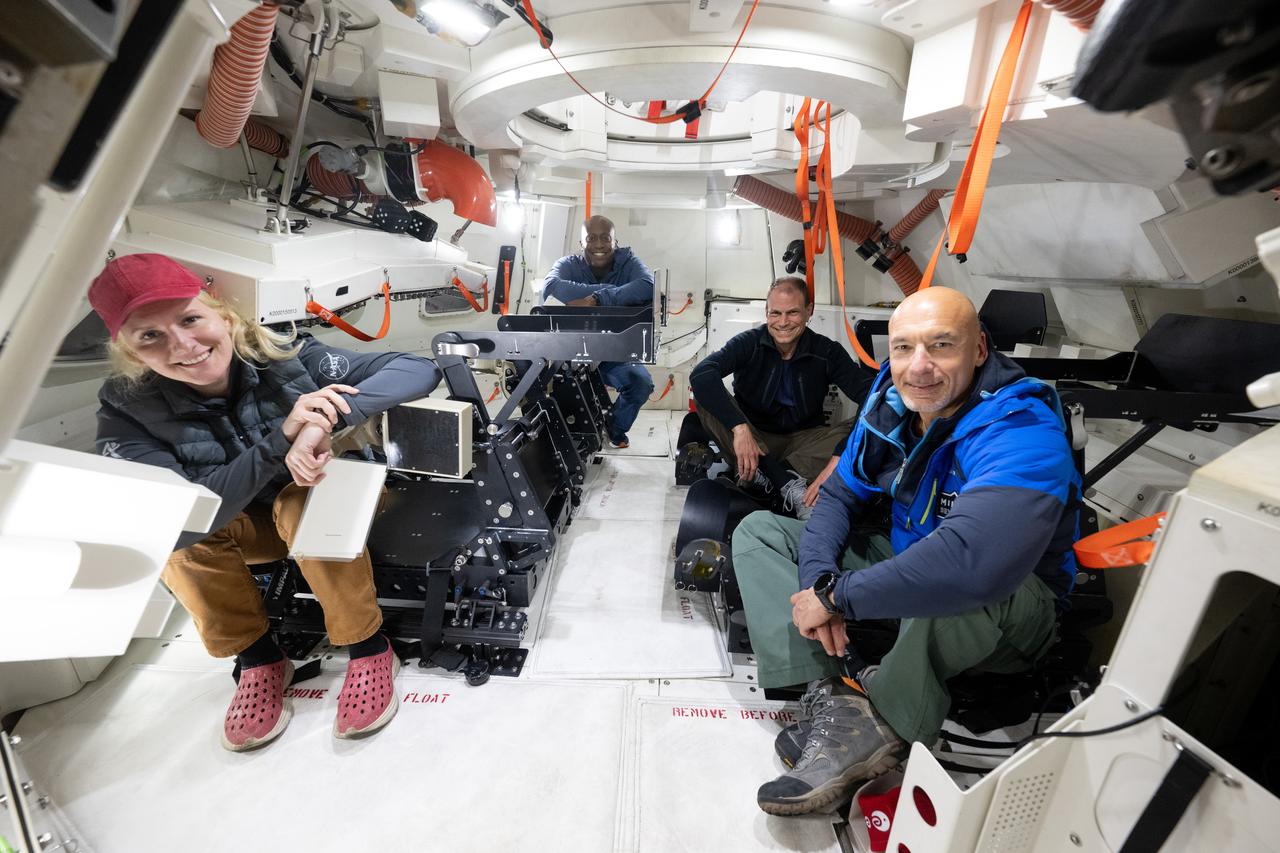 NASA astronauts Deniz Burnham, left, Andre Douglas, Stan Love, and ESA (European Space Agency) astronaut Luca Parmitano pose for a picture inside the Crew Module Test Article (CMTA), a full scale replica of the Orion spacecraft, as they prepare to participate in Underway Recovery Test-12 onboard USS Somerset, Tuesday, March 25, 2025. During the test, NASA and Department of Defense teams are practicing to ensure recovery procedures are validated as NASA plans to send the Artemis II astronauts around the Moon and splashdown in the Pacific Ocean.  Photo Credit: (NASA/Joel Kowsky)