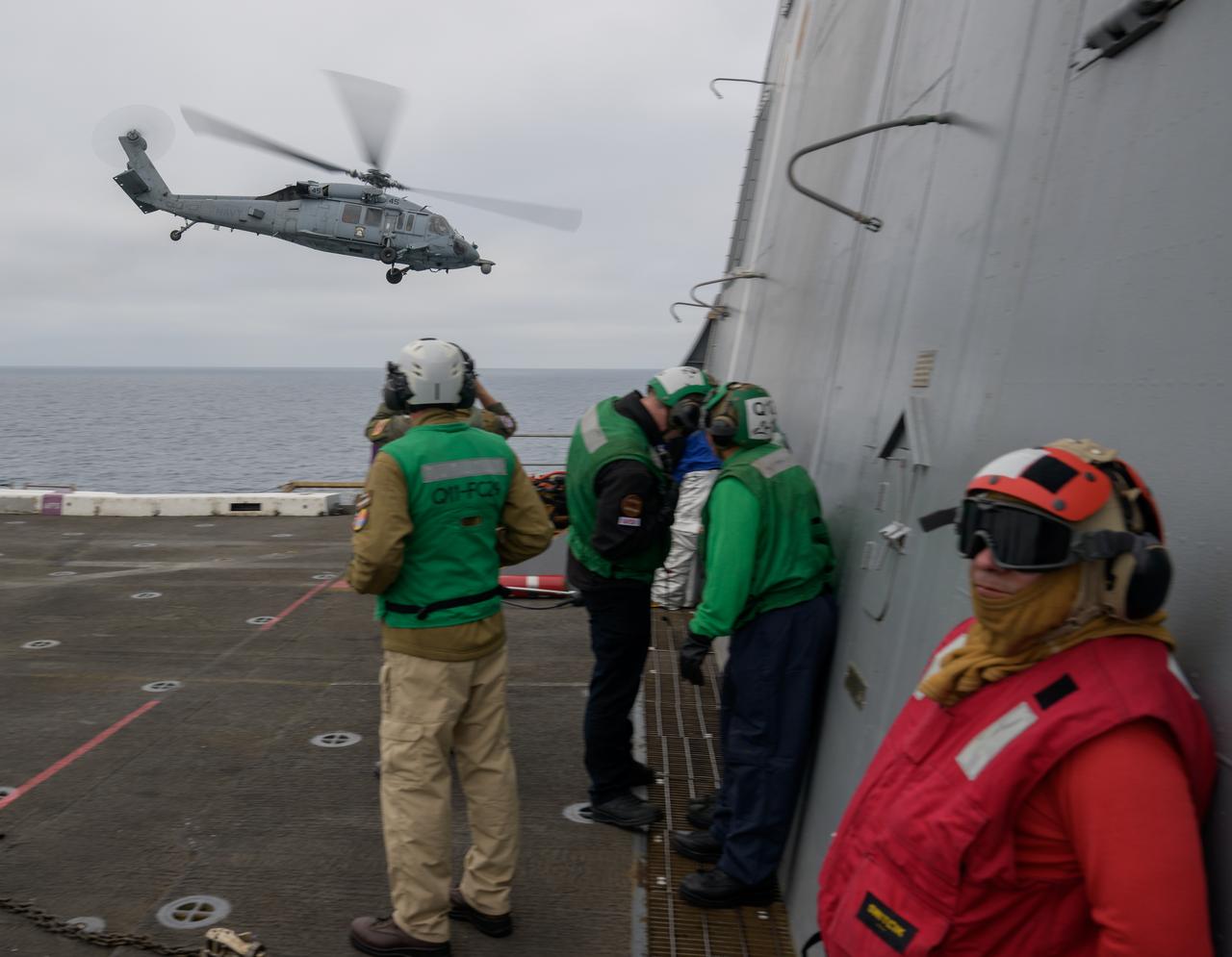 A helicopter flies by USS Somerset off the coast of California, as NASA and Department of Defense teams participate in Underway Recovery Test-12, Tuesday, March 25, 2025. During the test, teams are practicing to ensure recovery procedures are validated as NASA plans to send the Artemis II astronauts around the Moon and splashdown in the Pacific Ocean.  Photo Credit: (NASA/Bill Ingalls)