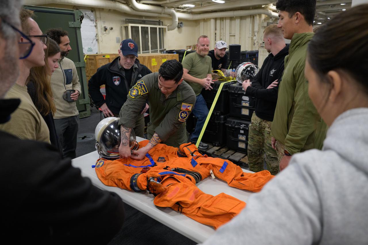 NASA and Department of Defense teams familiarize themselves with the pressure suits the Artemis II crew will be wearing when they return from their mission during Underway Recovery Test-12 onboard USS Somerset off the coast of California, Wednesday, March 26, 2025. During the test, NASA and Department of Defense teams are practicing to ensure recovery procedures are validated as NASA plans to send Artemis II astronauts around the Moon and splashdown in the Pacific Ocean. Photo Credit: (NASA/Joel Kowsky)