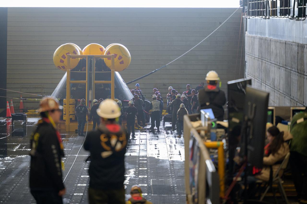 Teams work on the Crew Module Test Article (CMTA), a full scale mockup of the Orion spacecraft, as it sits sits nestled in its cradle during Underway Recovery Test-12 onboard USS Somerset off the coast of California, Wednesday, March 26, 2025. During the test, NASA and Department of Defense teams are practicing to ensure recovery procedures are validated as NASA plans to send Artemis II astronauts around the Moon and splashdown in the Pacific Ocean. Photo Credit: (NASA/Joel Kowsky)